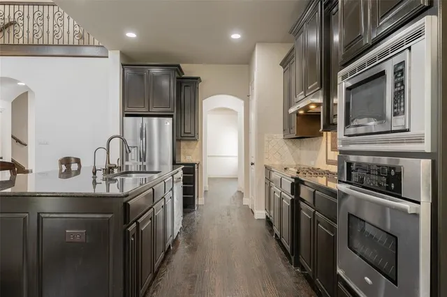 a kitchen with stainless steel appliances granite countertop a sink a stove and a refrigerator