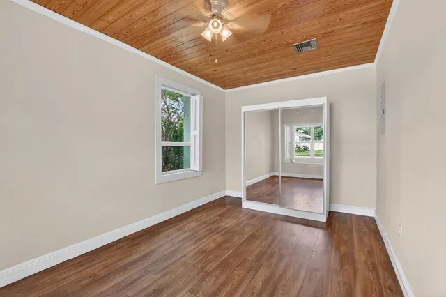 an empty room with wooden floor chandelier and windows