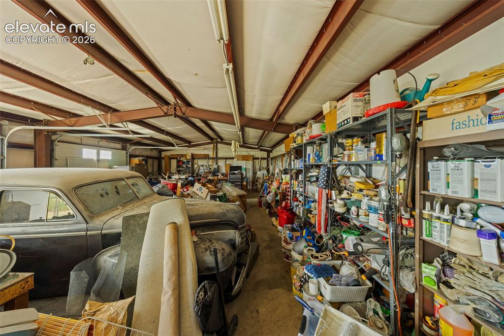 13075 Blaney Road South Peyton, CO 80831 - Photo 29 of 40 Expansive interior garage space featuring exposed steel beams and ample overhead lighting with room for 4+ cars.