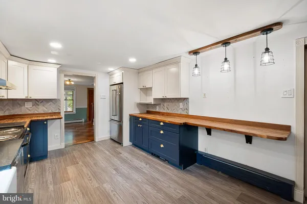 a kitchen with stainless steel appliances granite countertop a refrigerator a sink dishwasher a stove and white countertops with wooden floor
