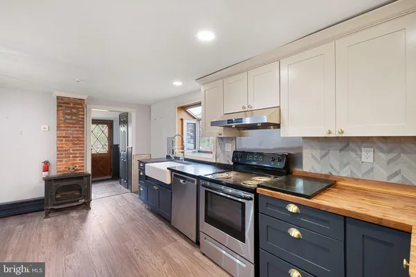 a kitchen with granite countertop a stove a sink wooden floor and cabinets