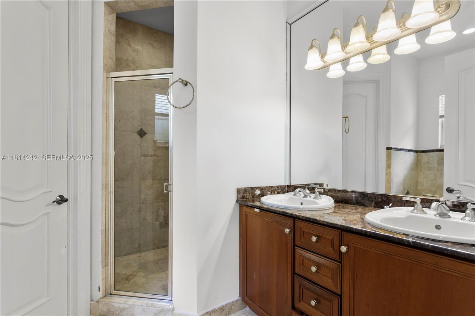 9339 Southwest 98th Place Miami, FL 33176 - Photo 30 of 33 a bathroom with a granite countertop sink a mirror and a shower