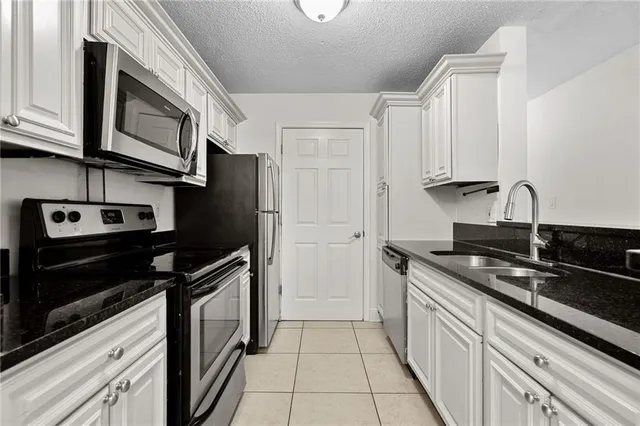 a kitchen with stainless steel appliances granite countertop white cabinets and black stove top oven with granite countertops