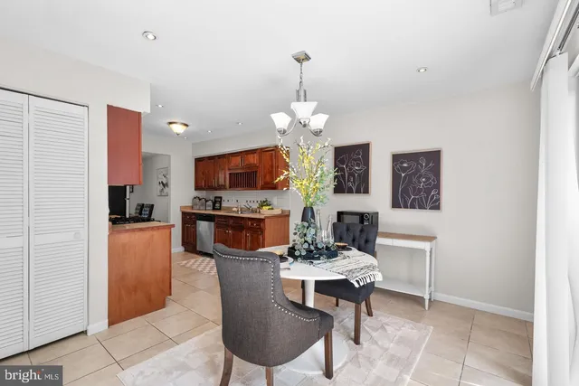 a dining room with furniture a chandelier a large window and stainless steel appliances