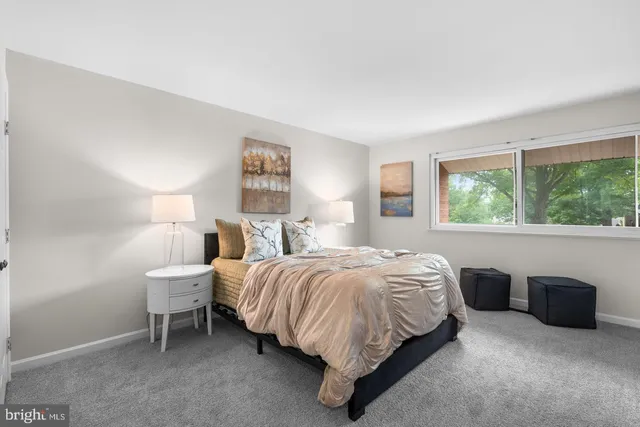 a bedroom with a bed lamp and a large window
