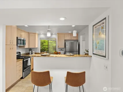 a kitchen with stainless steel appliances a stove top oven a refrigerator a dining table and chairs