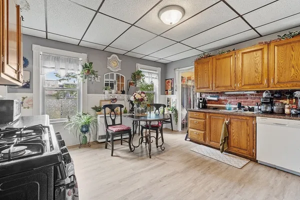 a kitchen with stainless steel appliances granite countertop a stove top oven a sink dishwasher a dining table and chairs with wooden floor