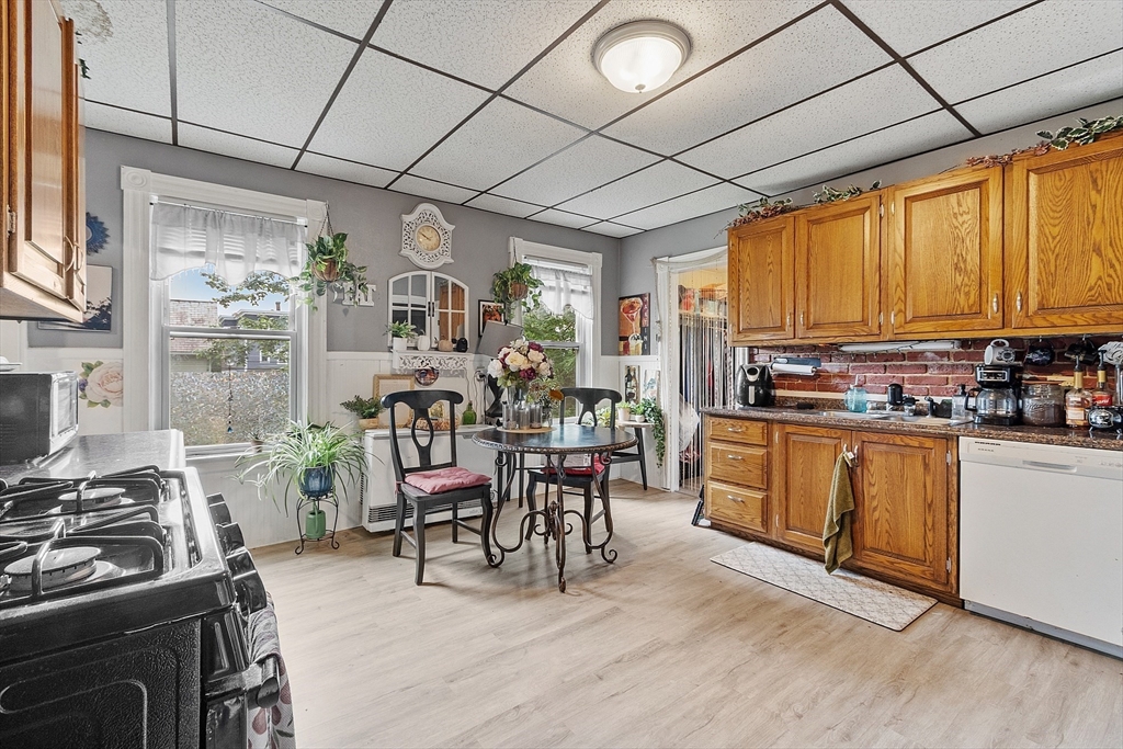 132 Hazel Street Fitchburg, MA 01420 - Photo 3 of 26 a kitchen with stainless steel appliances granite countertop a stove top oven a sink dishwasher a dining table and chairs with wooden floor