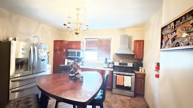 a dining room with stainless steel appliances kitchen island granite countertop furniture and a chandelier