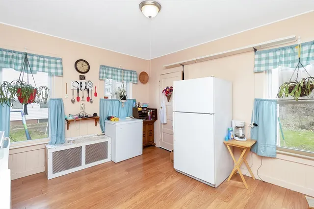 a kitchen with refrigerator and wooden floor