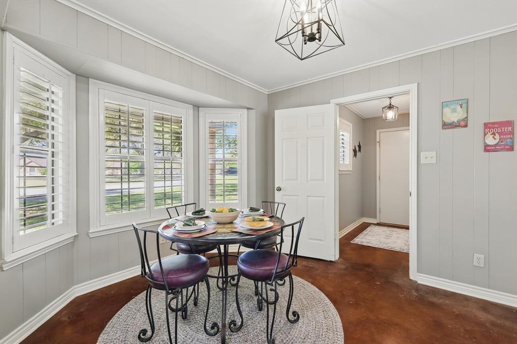 1904 Oak Ridge Trail Bridgeport, TX 76426 - Photo 13 of 34 Dining area featuring wooden walls, concrete floors, crown molding, and a chandelier