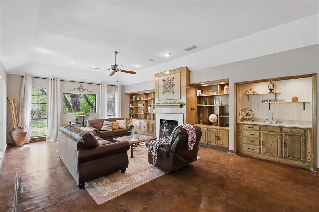1904 Oak Ridge Trail Bridgeport, TX 76426 - Photo 9 of 34 Living room featuring finished concrete floors, a fireplace, a ceiling fan, and built in features