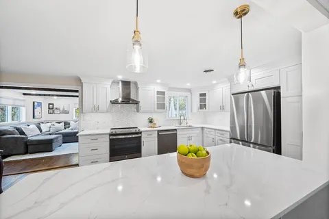 a kitchen with kitchen island a counter top space a sink stainless steel appliances and cabinets
