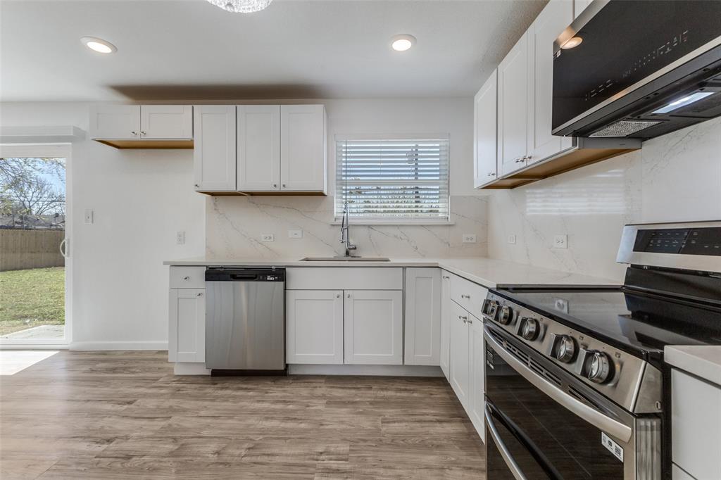 2950 Windmill Lane Farmers Branch, TX 75234 - Photo 11 of 25 a kitchen with stainless steel appliances a stove a sink and white cabinets