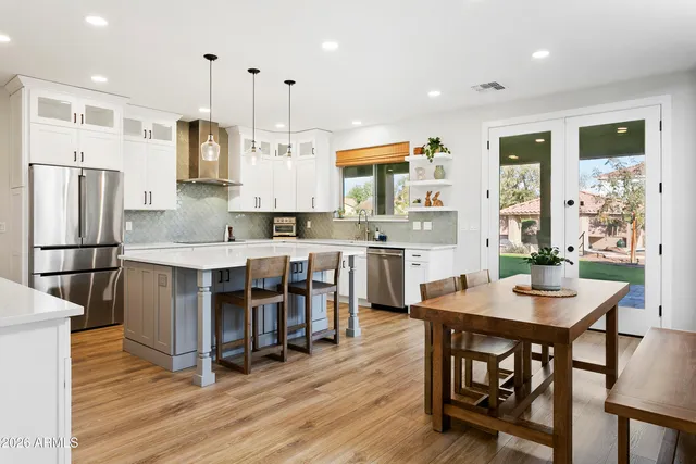 a kitchen with stainless steel appliances granite countertop a refrigerator a sink dishwasher a stove and white cabinets with wooden floor