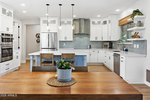 a kitchen with stainless steel appliances kitchen island granite countertop a refrigerator a stove a sink dishwasher and white cabinets with wooden floor