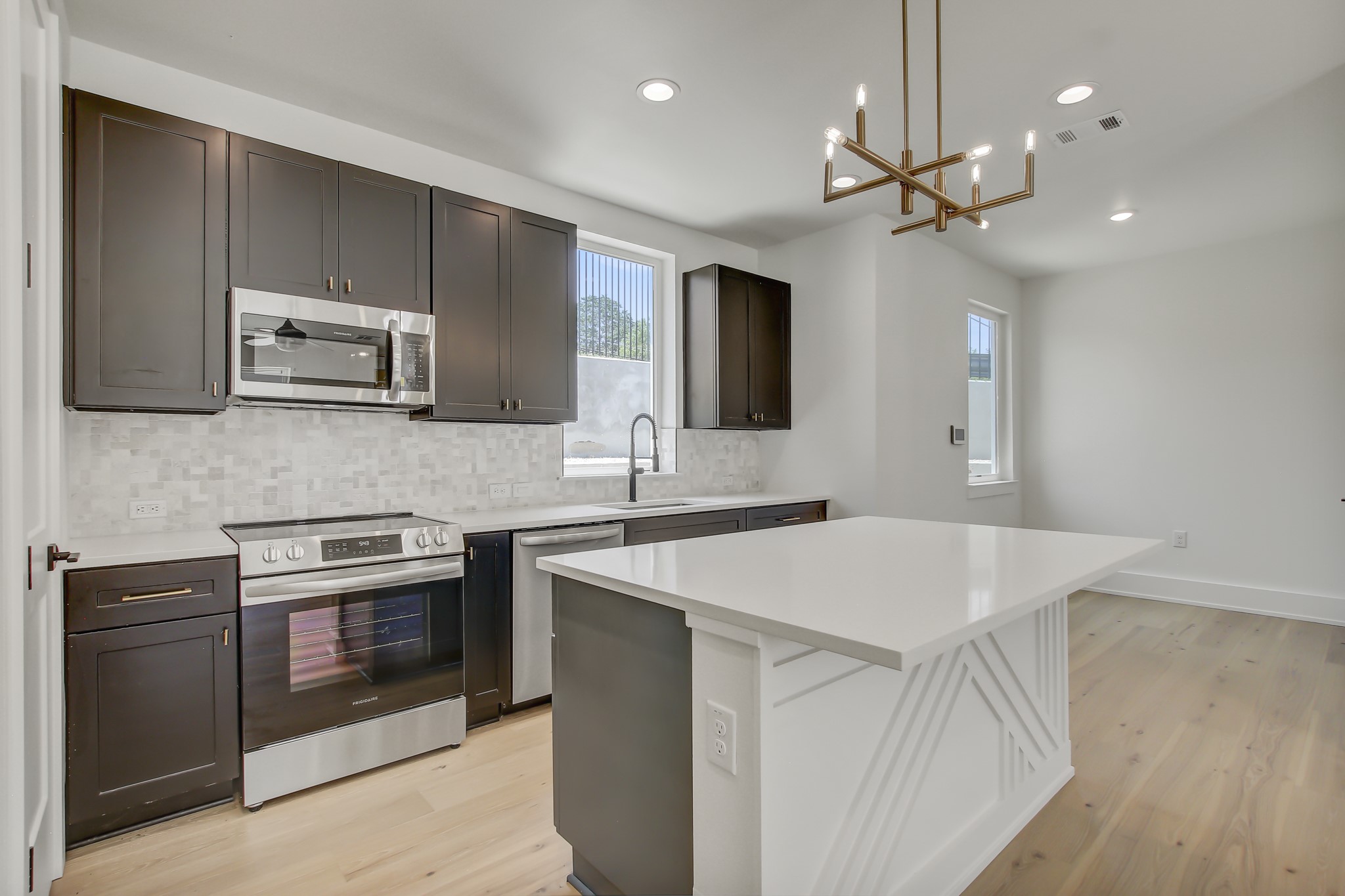 4127 East 12th Street, Unit 8 Austin, TX 78721 - Photo 2 of 32 Kitchen featuring appliances with stainless steel finishes, a sink, tasteful backsplash, light wood finished floors, and a chandelier