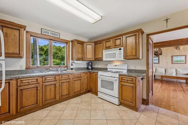 a kitchen with stainless steel appliances granite countertop a stove top oven a sink dishwasher a dining table and chairs with wooden floor