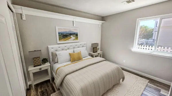 a bedroom with a bed television on desk and a window