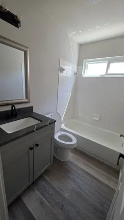 a bathroom with a granite countertop toilet sink and mirror