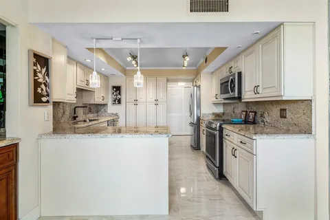 a room with stainless steel appliances kitchen island granite countertop a refrigerator and cabinets