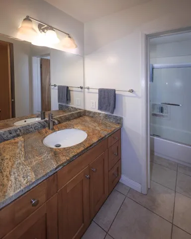 a bathroom with a granite countertop sink and a mirror