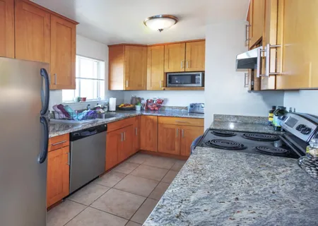 a kitchen with stainless steel appliances granite countertop a sink stove refrigerator and cabinets