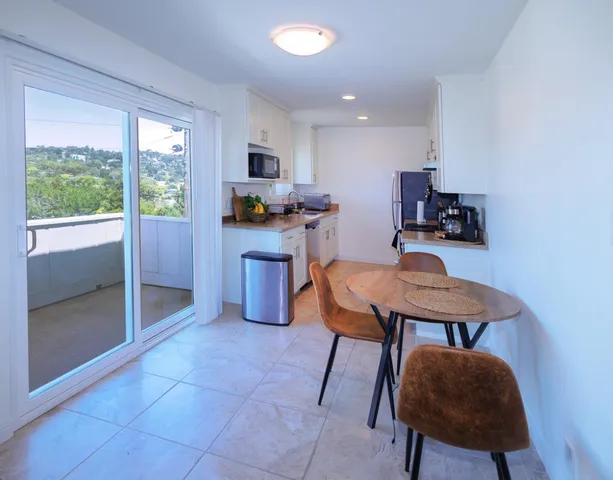 a kitchen with stainless steel appliances a table chairs refrigerator and sink