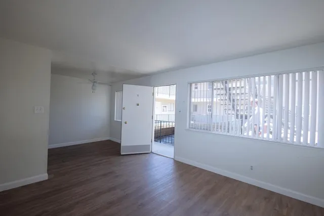 a view of an empty room with wooden floor and a window