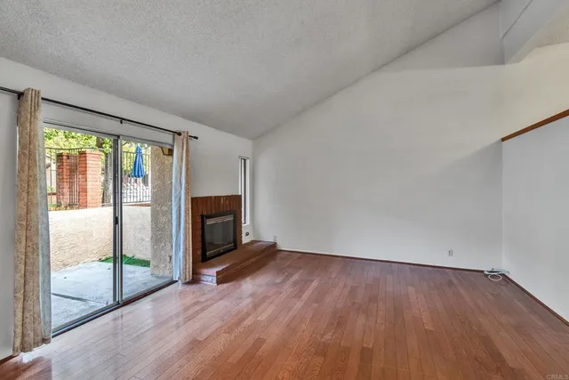a view of empty room with wooden floor and fireplace