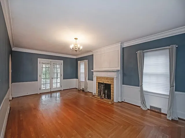 an empty room with wooden floor fireplace and windows
