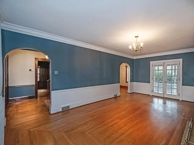 a view of an empty room with window and wooden floor