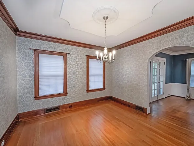 a view of an empty room with window and wooden floor