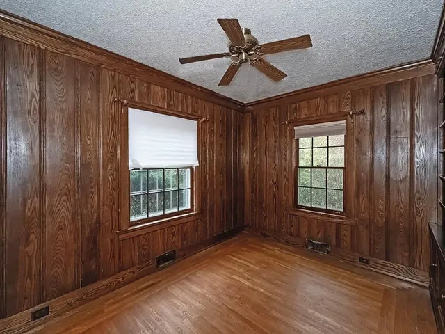 a view of an empty room with a window and wooden floor