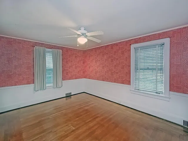 an empty room with windows and fan