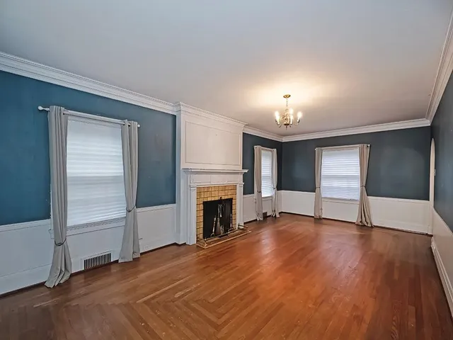 an empty room with wooden floor fireplace and windows
