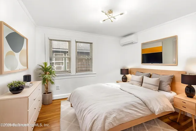 a bedroom with a bed table flowerpot and window