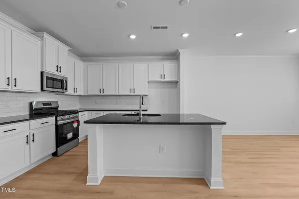 a kitchen with stainless steel appliances granite countertop a sink a stove top oven a counter space and cabinets