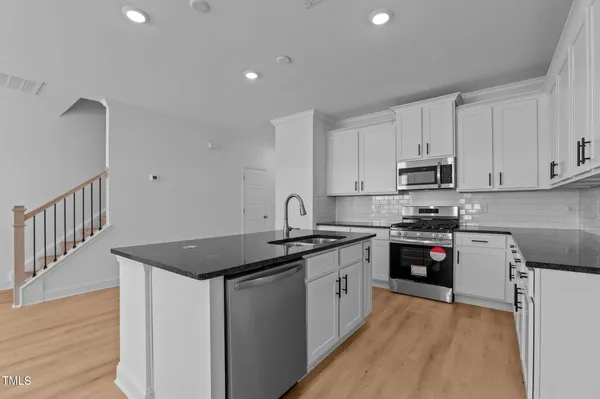 a kitchen with stainless steel appliances granite countertop a table chairs sink and cabinets