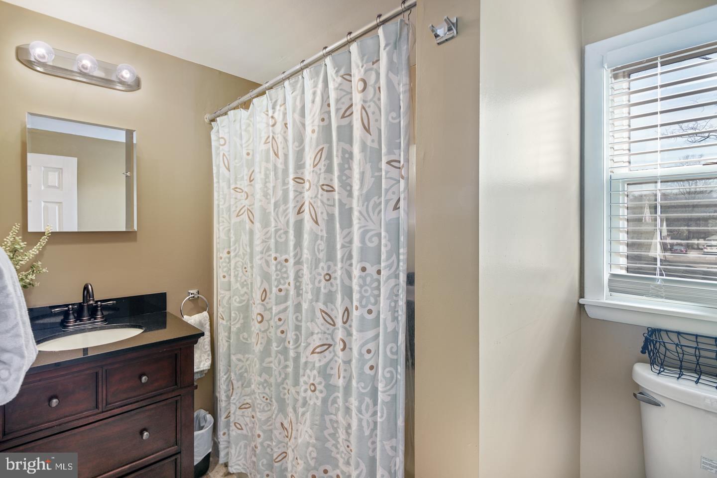 1025 Chesterfield Road Barrington, NJ 08033 - Photo 26 of 32 a bathroom with a sink a mirror and a shower curtain