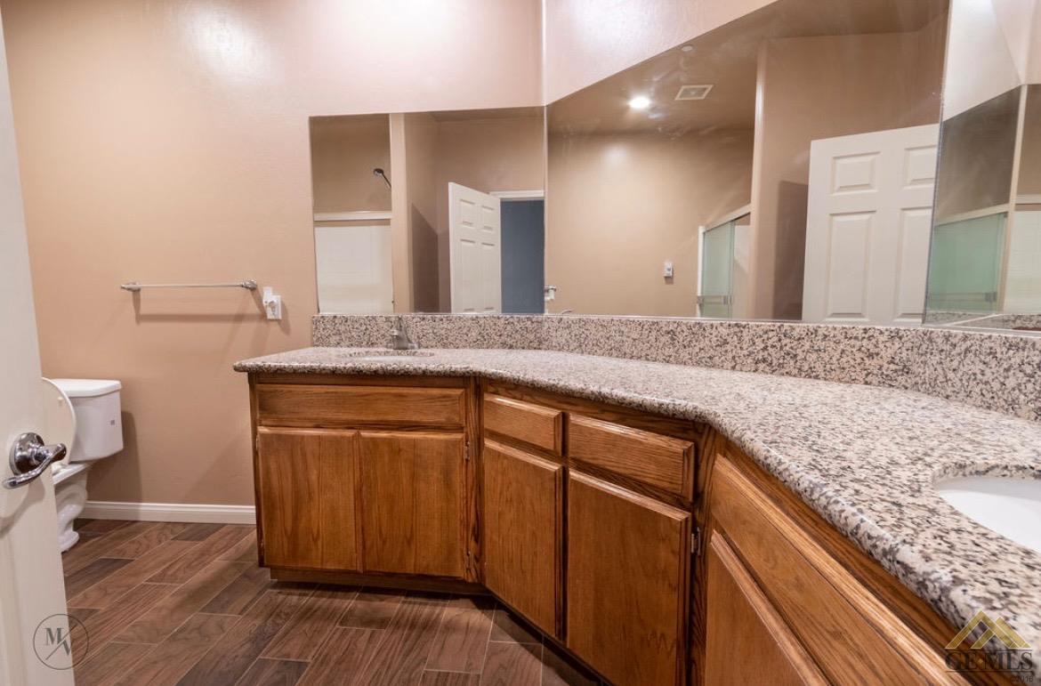 Undisclosed Address Wasco, CA 93280 - Photo 12 of 28 a bathroom with a granite countertop sink a toilet and a large mirror