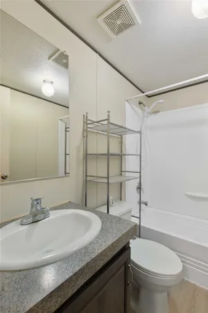 a bathroom with a granite countertop sink a toilet a mirror and shower