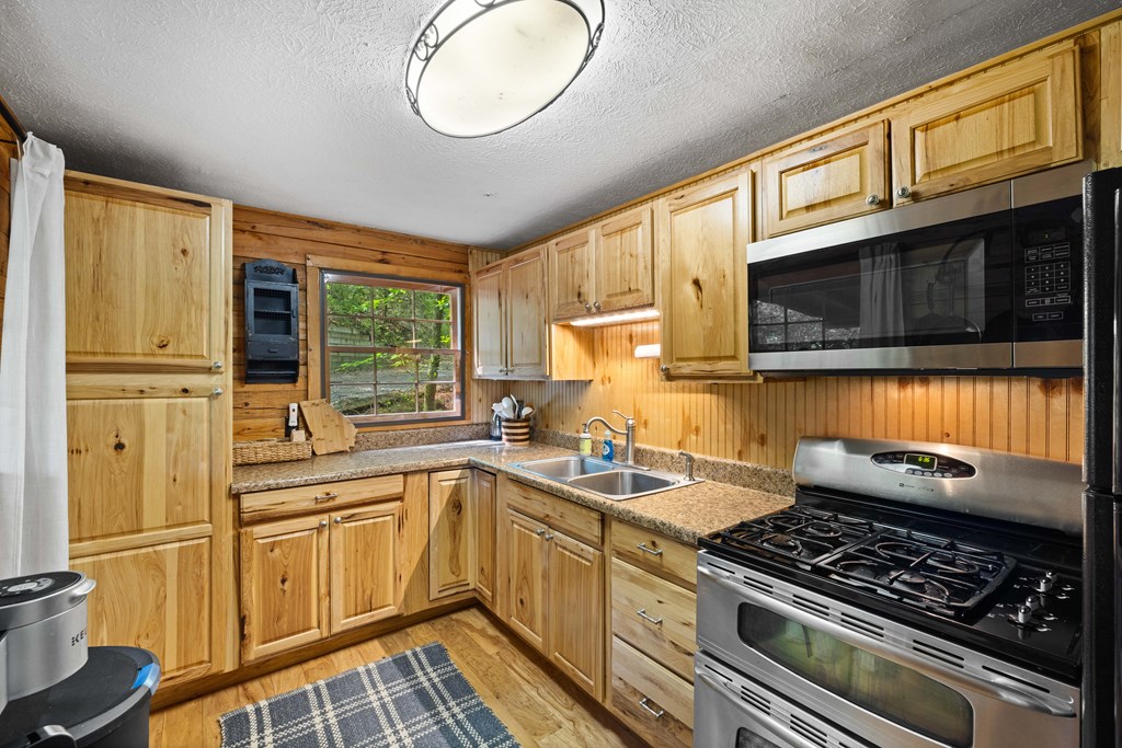 459 Mill Stone Mountain Lane Blue Ridge, GA 30513 - Photo 6 of 25 a kitchen with stainless steel appliances granite countertop a stove a sink dishwasher and a microwave oven with cabinets