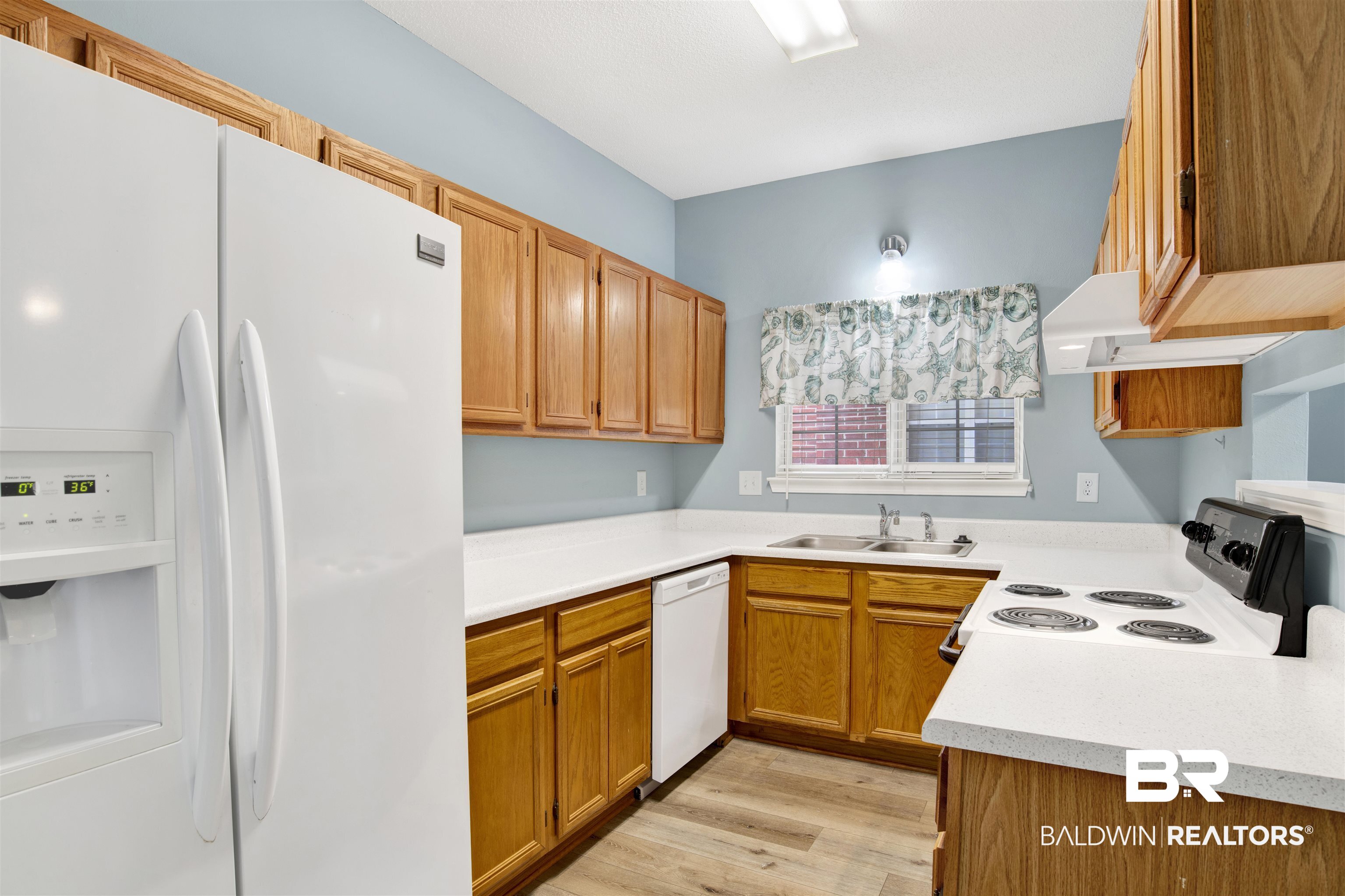 1258 Sutton Court, Unit 4 Mobile, AL 36609 - Photo 9 of 19 Kitchen with brown cabinets, a sink, light countertops, white appliances, and light wood-style flooring