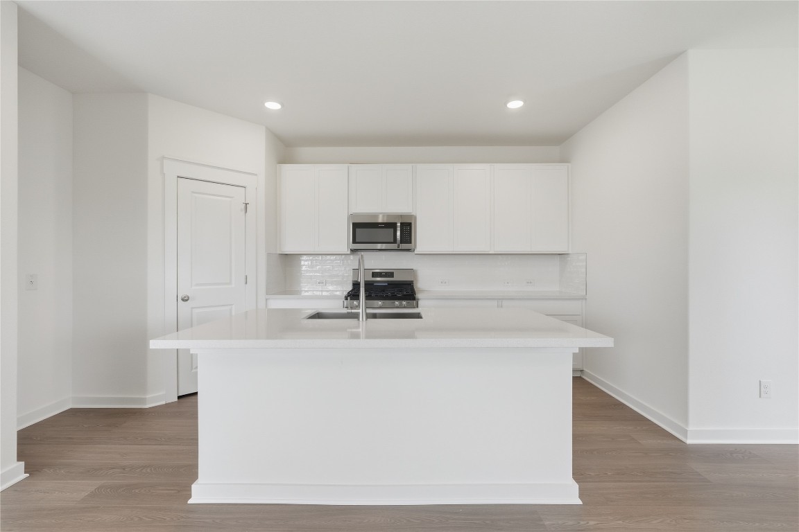 13501 Barn Chime Street Elgin, TX 78621 - Photo 2 of 19 a kitchen with kitchen island a sink a stove a microwave and cabinets