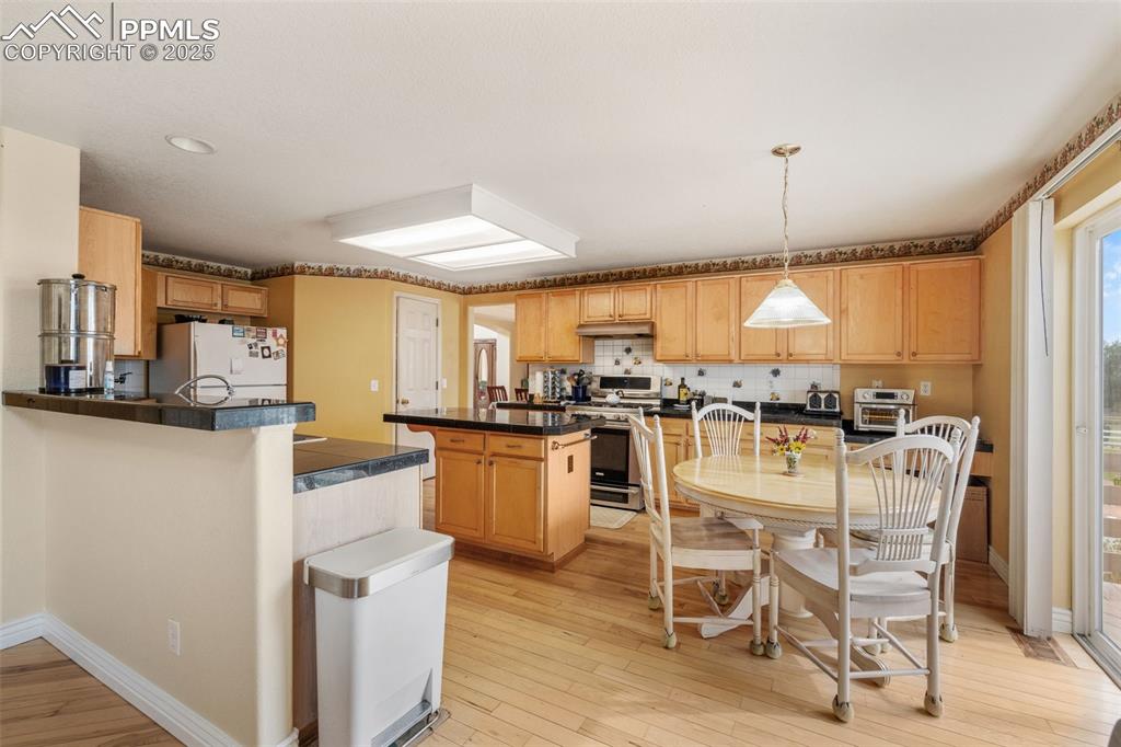 8654 Champie Road Peyton, CO 80831 - Photo 14 of 40 a kitchen with stainless steel appliances kitchen island granite countertop a table chairs and a view of living room