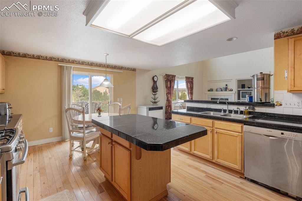8654 Champie Road Peyton, CO 80831 - Photo 16 of 40 a kitchen with stainless steel appliances granite countertop a kitchen island hardwood floor sink stove dining table and chairs