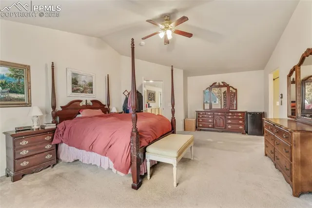 a spacious bedroom with a bed a dresser and a chandelier