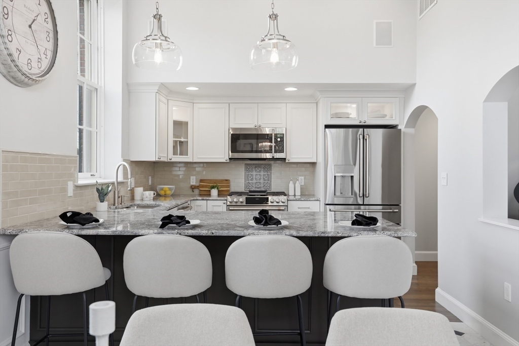 83 Church Street, Unit 15 Winchester, MA 01890 - Photo 11 of 34 a kitchen with stainless steel appliances a white table chairs and a refrigerator