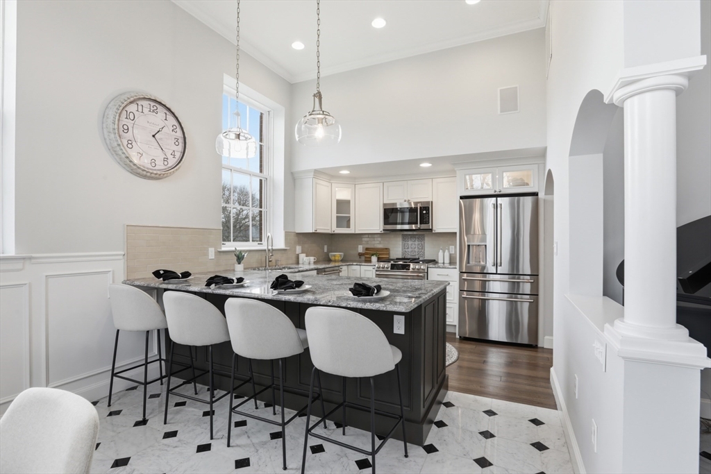 83 Church Street, Unit 15 Winchester, MA 01890 - Photo 10 of 34 a kitchen with stainless steel appliances a table chairs and a refrigerator